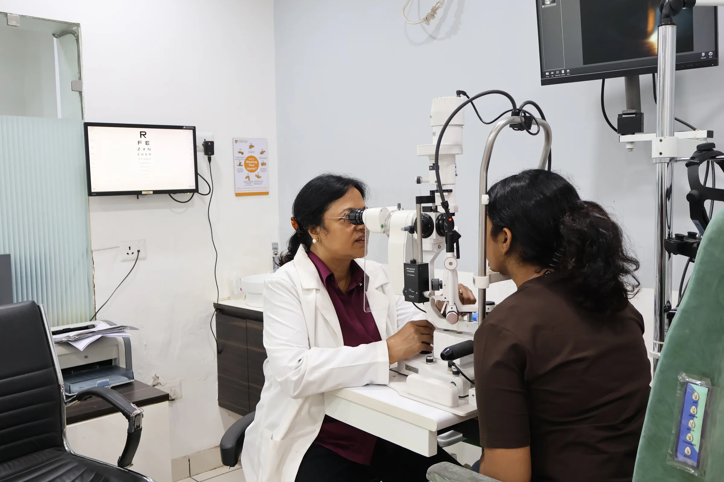 Dr. Poonam Jain examining a patient at a slit-lamp unit in a consultation room