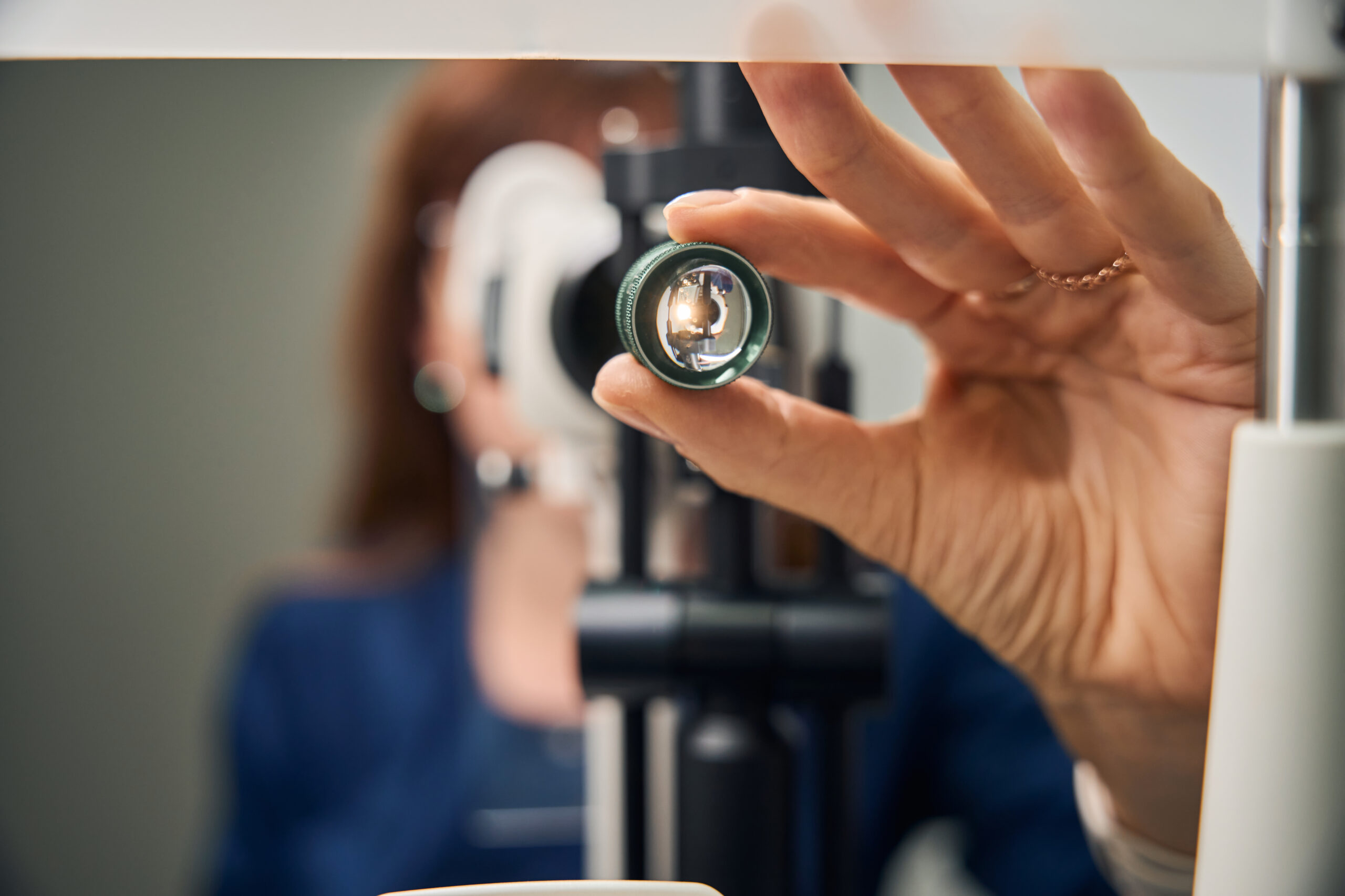 Close-up of an optometrist's hand adjusting the slit lamp lens, preparing for a detailed eye exam