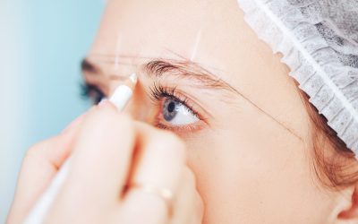 Cosmetolog beauty master making marks with pencil before the permanent makeup procedure.