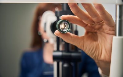 Close-up of an optometrist's hand adjusting the slit lamp lens, preparing for a detailed eye exam