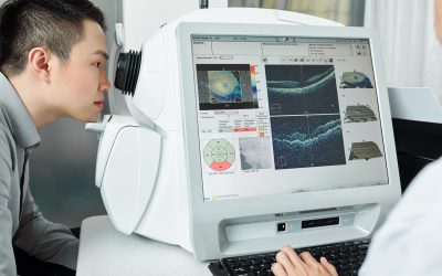 Asian young patient checking his eyesight on special medical equipment with doctor at hospital